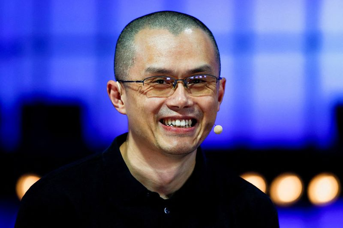 The image features a man with short hair wearing glasses, smiling at the camera. The background of the photo shows a blue wall with lights behind him, suggesting that he might be speaking at an event or presentation. There are also some text elements present in the image, including the words "Maalesef" and "$SUI", which could potentially be related to his name or the organization hosting the event where he is speaking.