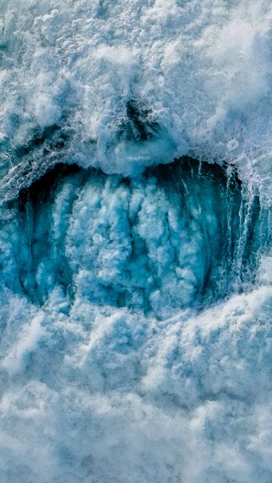 A close-up view shows the textured, icy blue surface of what appears to be a frozen waterfall or glacier cave.