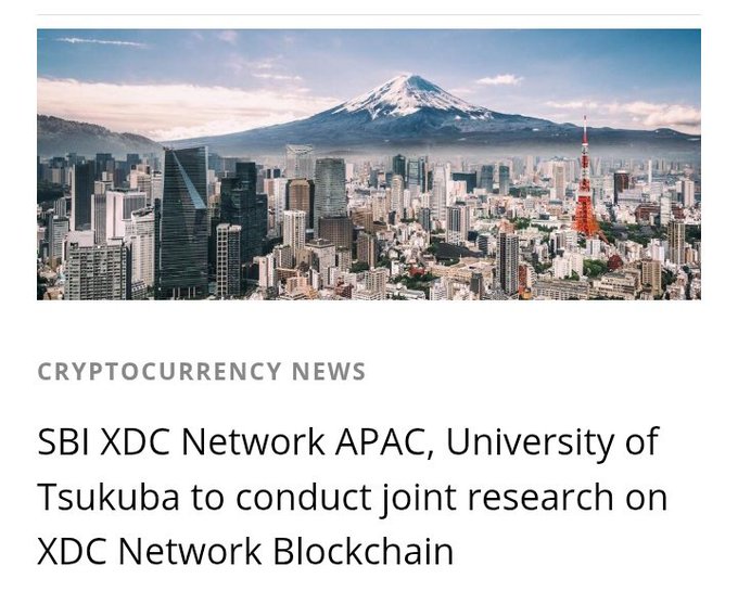 The image shows a cityscape with a mountain range in the background, along with text that reads "Cryptocurrency News" and "SBI XDC Network APAC University of Tsukuba team up for blockchain research fxnewsgroup.com/forex-news/cry". The focus on this image is to promote Cryptocurrency news and educate people about the latest developments in the field, specifically related to SBI XDC Network's collaboration with the University of Tsukuba to conduct research on blockchain technology.
