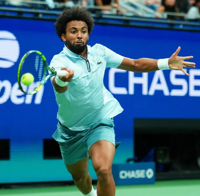 A tennis player in a light blue Lacoste outfit swings his racket to hit a yellow ball during a match, with "CHASE" visible on the blue backdrop behind him. The image illustrates a Polymarket trader's $35,127 bet on Arthur Fils to defeat Stefanos Tsitsipas at the US Open.