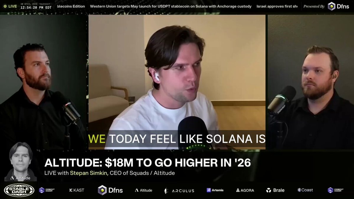 The image shows a news broadcast with three men sitting behind microphones, talking about Bitcoin and cryptocurrency. The first man is wearing a white shirt and has his back turned towards the camera. The second man is wearing a black shirt and is facing the camera directly. The third man is also wearing a black shirt but is looking away from the camera. They are discussing the benefits of using Bitcoin for payments, with one man saying that it's like Solana, another referring to it as Altitude 18M, and the third talking about going higher in 26.