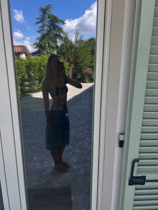The image features a woman standing in front of a window with her back facing the camera. She appears to be taking a selfie or capturing a moment from outside through the glass window. The background includes trees, indicating that she might be outdoors. The photo has been edited and captioned "Gm CT a little sunshine, a little reflection a little peace". This suggests that the woman is enjoying her time outdoors in front of the window, possibly taking advantage of the natural light or capturing a pleasant moment outside.

The image also includes a door with a lock on it, which adds an interesting detail to the scene and contrasts with the woman's activity. The combination of these elements creates a visually appealing composition that highlights both the subject (the woman) and her surroundings.