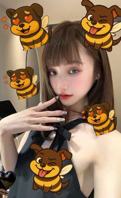 The image features a woman with brown hair wearing a black dress, posing for a picture surrounded by various cartoon bee stickers. The stickers are arranged around her face, neck, and shoulders, creating an interesting and playful atmosphere. The caption of the image reads "Talking about that female KOL, it'S Shi Jiaying, right? @JYinG_eth In early 2024-2025, she quickly gained nearly 10,000 followers through selfies, packaging herself as the 'hot girl who's both beautiful and knows her meme coins'. Focus on what is in the image and how it relates to the post."