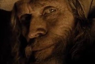 A close-up portrait of a bearded man with long hair, appearing weary or contemplative, with dramatic lighting highlighting his weathered face.
