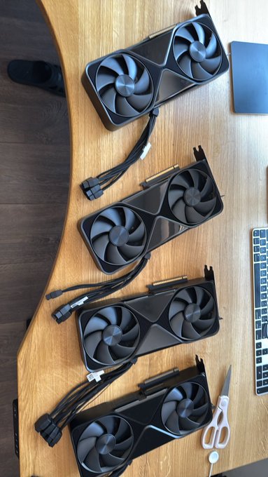 Four NVIDIA Founders Edition graphics cards are lined up vertically on a wooden desk, labeled as "Beasts" to emphasize their powerful computing capabilities, ready for use in a multi-GPU setup alongside a keyboard and scissors.