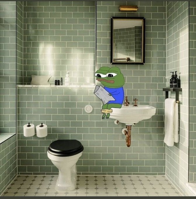 A vintage-style bathroom with green subway tiles, featuring a cartoon Pepe the Frog sticker pasted on the wall, appearing to read a newspaper while sitting on the sink.
