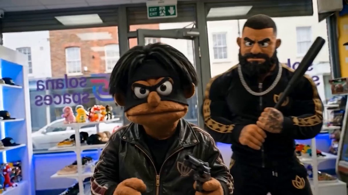 The image features two men dressed up as characters from a popular cartoon series, with one man wearing a black jacket and holding a gun while the other man wears a black shirt and has a fake mustache. The background includes a store window display showcasing various items for sale. There is also a car visible in the scene. The post appears to be related to the cartoon show "SEC #3" as it mentions that the character Missed it live last Thursday, which could potentially be an indication of a special event or release date.