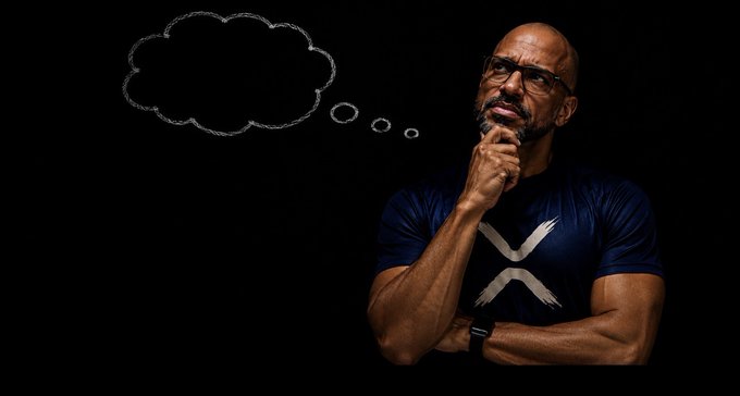 A man with glasses and a dark t-shirt stands in thought with his hand on his chin against a black background, with a blank chalk-drawn thought bubble beside him.