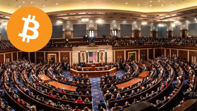 The image shows the interior of the United States House of Representatives chamber, filled with members seated in the iconic curved arrangement of desks, with the Speaker's rostrum and American flag at the center, overlaid with a large orange Bitcoin (₿) logo in the upper left corner, visually linking the legislative vote on the Clarity Act (scheduled for 3:15 a.m. Japan time on the 16th) to potential cryptocurrency regulation.