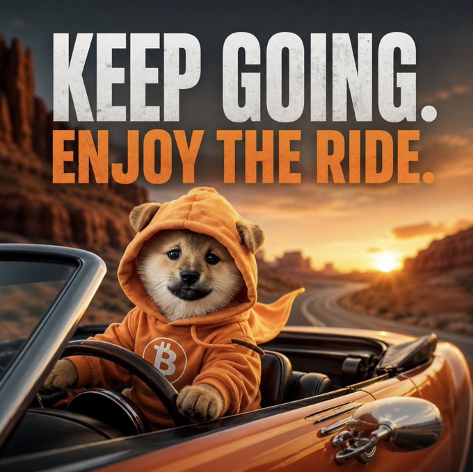 A motivational poster featuring a Shiba Inu dog wearing an orange Bitcoin hoodie while driving a convertible, with the text "KEEP GOING. ENJOY THE RIDE." set against a desert sunset.