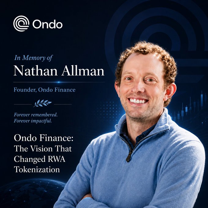 The image features a man wearing a blue sweater with his arms crossed over his chest. The background of the image is dark blue, which contrasts with the man's light-colored sweater. There are two circles in the image, one larger than the other, positioned above and below the man. The text "In memory of Nathan Allman" is written on the image, indicating that it is a tribute to him.