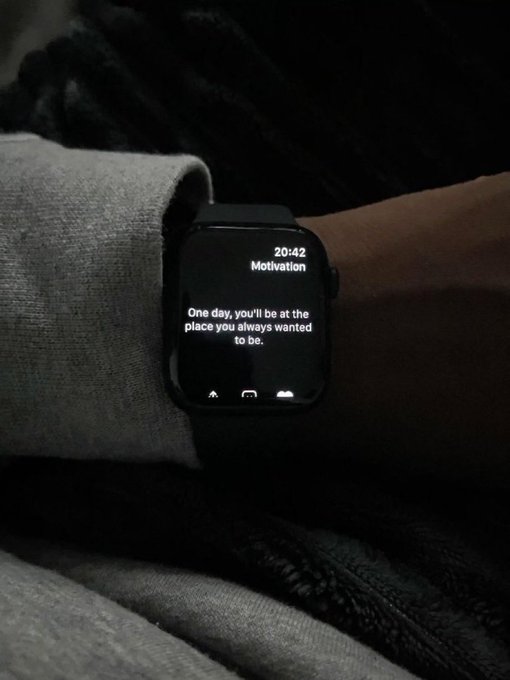 A wrist wearing a smartwatch displaying a motivation quote: 'One day, you'll be at the place you always wanted to be' at 20:42.