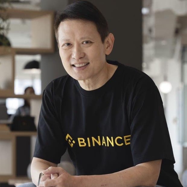 A smiling man wearing a black t-shirt with the yellow Binance logo sits at a table in a casual setting. The image relates to the post by depicting Binance CEO Richard Teng, who is credited in the accompanying news about the company's role in helping Indian authorities dismantle a darknet drug trafficking network through blockchain tracing.