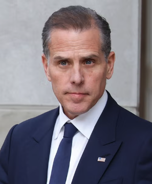 A portrait photo of Hunter Biden wearing a dark blue suit, white shirt, and blue tie with an American flag pin.
