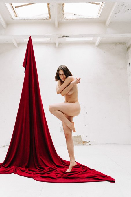 A nude woman stands in a graceful pose next to a dramatic drape of red fabric, embodying the title "Weightless" and the associated NFT details "1/1, 250 xtz".