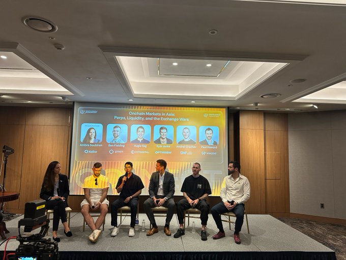 A panel of six speakers sits on stage at the Cointelegraph Connect Seoul Edition event, with a presentation slide behind them titled "Onchain Markets in Asia: Perps, Liquidity, and the Exchange Wars" featuring headshots of panellists Ambre Soubiran (Kaiko), Ben Fielding (Gensyn), Augie Ilag (CMT Digital), Kyle Jansa (Optimism), Andrew Durkin (DWFLabs), and Paul Howard (Wincent), as they discuss Asian onchain markets.