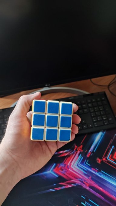 The image shows a person holding up a Rubik's cube, which has blue squares on a yellow background. The person appears to be showing off their Rubik's cube or possibly explaining its structure. The image also contains text that reads "focus on what is in the image and how it relates to the post @base because community feedback is just as important as clean code." This message emphasizes the importance of sharing progress, knowledge, and ideas within a community for the betterment of projects like Rubik's cube or cryptocurrency development.