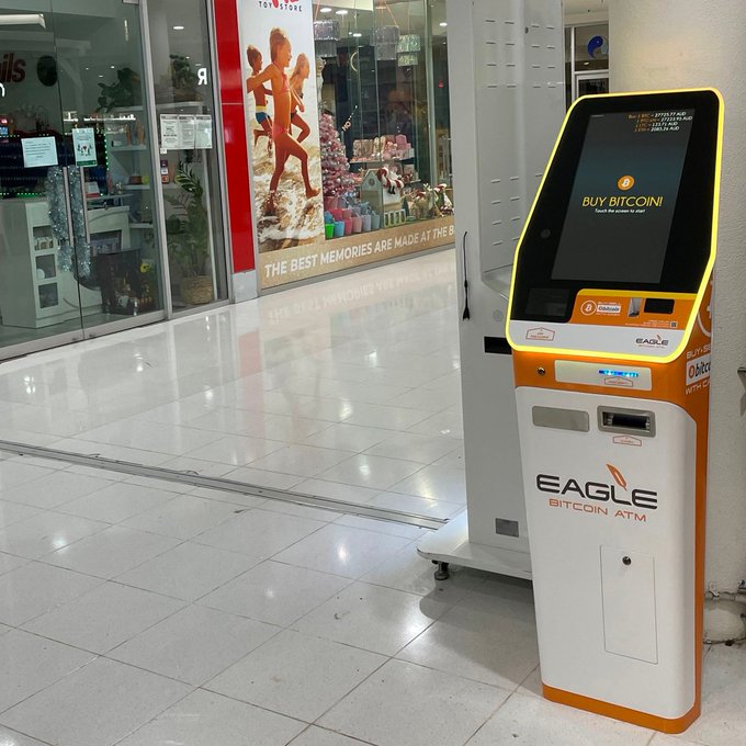 An orange and white "EAGLE Bitcoin ATM" stands inside a brightly lit shopping center, its screen prompting users to "BUY BITCOIN," illustrating the post's claim about Bitcoin's growing presence in everyday Australian locations.
