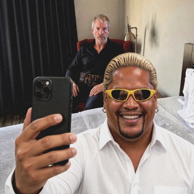 An AI-generated image showing a smiling man in yellow sunglasses taking a selfie in the foreground, while an older man with grey hair sits suspiciously in the background chair.