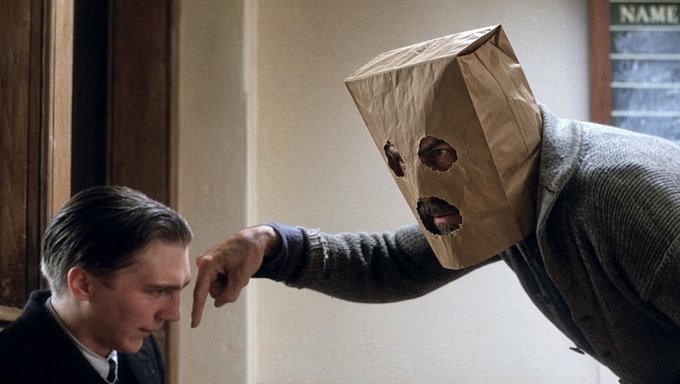A meme scene from a film showing a man in a suit being yelled at by a figure wearing a brown paper bag with eye and mouth holes over his head.