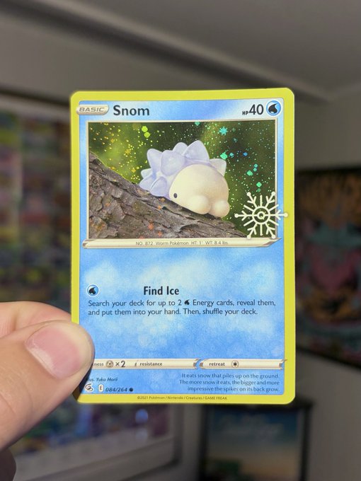 A hand holding a holographic Pokémon trading card featuring Snom, a basic Water-type card from the Silver Tempest set.