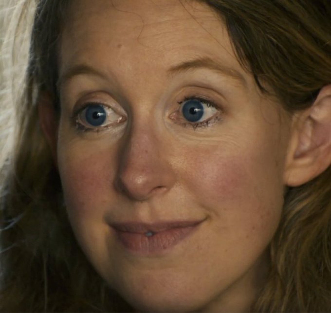 A close-up selfie of a wide-eyed, slightly flushed woman with an intense, unblinking stare and a subtle, somewhat unsettling smile, perfectly capturing the incredulous, deadpan expression of someone processing a ridiculous confession.