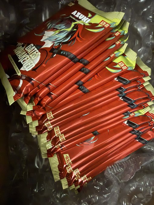 A pile of red and yellow "AZUKI" instant noodle packets with anime-style artwork, displaying "120g" on the packaging.