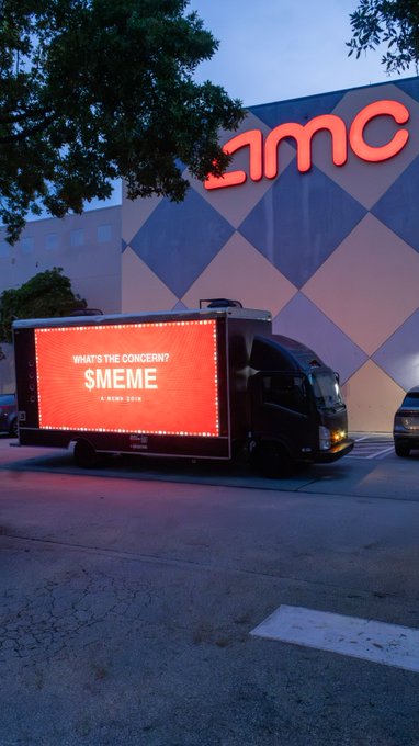 A digital billboard truck displays "WHAT'S THE CONCERN? $MEME 5 JUNE 2018" parked in front of an AMC theater, promoting the meme coin's marketing campaign to drive visibility at cinema locations.