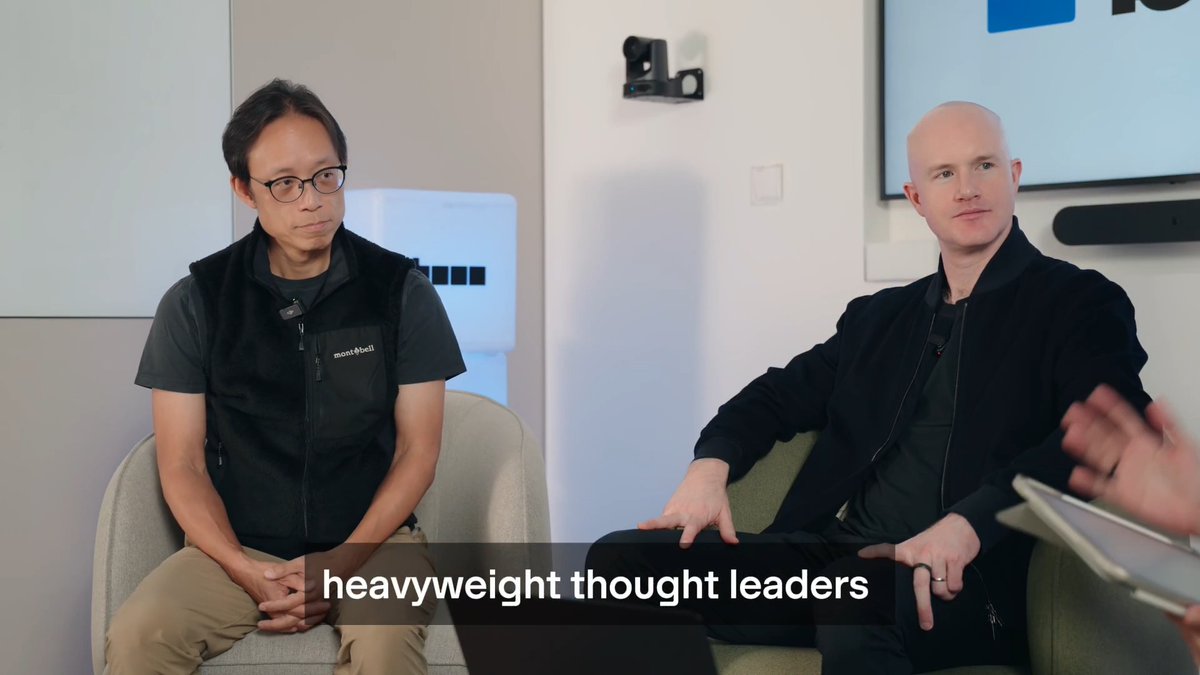 Brian Armstrong and Yat Siu sit side-by-side in a discussion setting, with the on-screen caption "heavyweight thought leaders" highlighting their conversation about AI's current state and whether it's overvalued, as previewed by the post's timestamps.