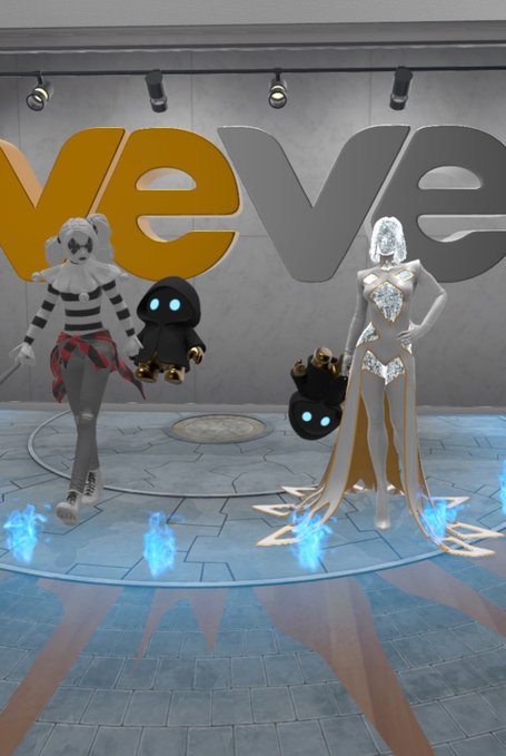 The image features two cartoon characters, a man and a woman, standing next to each other with their arms around each other's shoulders. They are positioned against a backdrop of a sign that says "VEVE" and another sign that reads "Happy Father's Day!". The scene is set in an indoor space, possibly a store or a convention center.