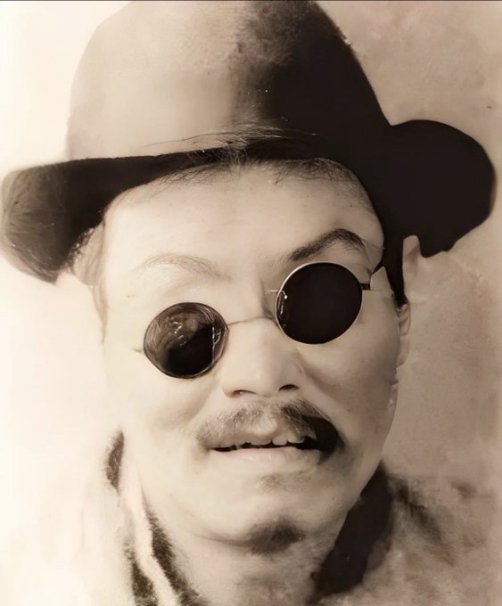 The image is a vintage black-and-white portrait of a man wearing a wide-brimmed hat, round dark sunglasses, and a fur-collared coat, with a mustache and slightly open-mouthed smile. Given the context, the post is humorously comparing this figure—Wang "Short Bird," claimed father of OKX—to "Ah Bing" from the famous Chinese sketch *Erquan Yingyue*, both referencing the round dark spectacles, suggesting OKX's token should be nicknamed "Ah Bǐng" (Ah Pie) as a play on the existing "Er Bing" (Second Pie) moniker.