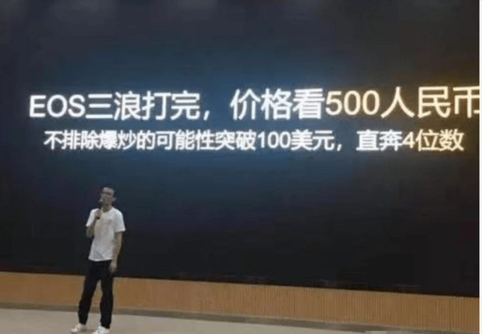 A man stands on a stage giving a presentation in front of a large screen displaying Chinese text about EOS price predictions, including 'EOS三浪打完,价格看500人民币' and '不排除爆炒的可能性突破100美元,直奔4位数'.