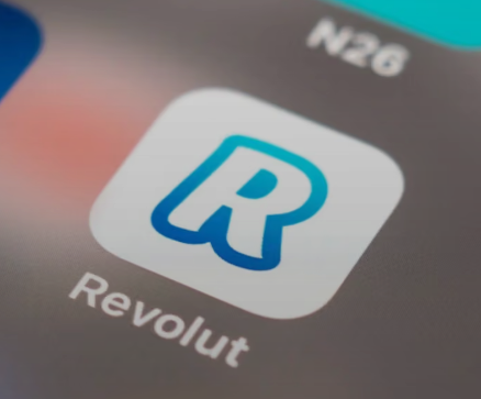 The image shows a close-up of a smartphone screen displaying the Revolut app icon, with the N26 banking app partially visible in the background. The accompanying post highlights a serious security lapse in which Revolut inadvertently disclosed sensitive user data—including passports, selfies, and Bitcoin transaction histories—to a spoofed government agency email that passed all authentication checks.