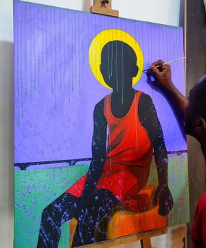 A painter's hand is visible applying paint to a canvas depicting a silhouetted figure with a yellow halo against a purple background.