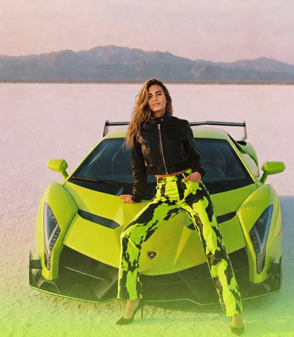 A woman poses confidently against a vibrant green Lamborghini on a salt flat, wearing a black leather jacket and green tie-dye pants that match the car's bold color—a perfect visual for the "Wen Lambo" movement gaining traction among models on Robinhood.