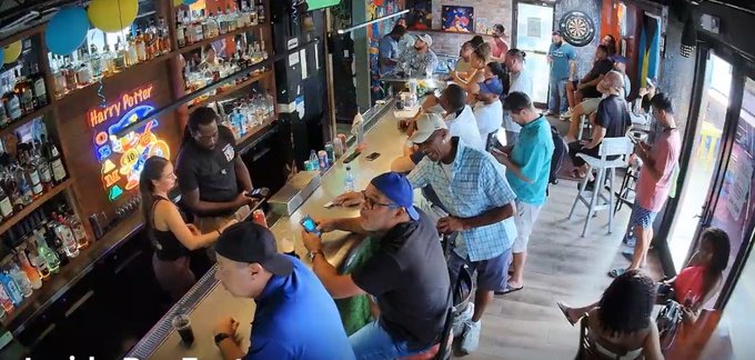 A bustling bar scene captured from a high angle shows a bartender serving customers, with a 'Harry Potter' neon sign and a dartboard visible in the background.