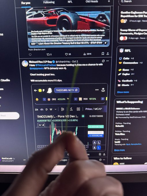 A computer monitor displaying X (formerly Twitter) feeds, with a hand pointing at a post from Richard Heart (@RichardHsu) about THICCUM/METH token, showing a crypto price chart and candlestick data.