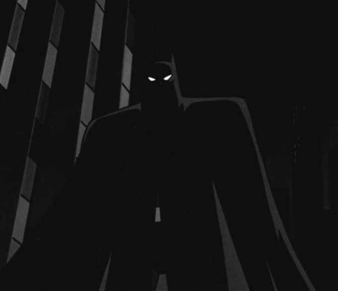 A dark, animated silhouette of Batman stands menacingly with glowing white eyes against a shadowy background.
