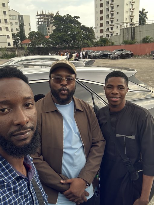 Three men pose for a selfie in a parking lot, with cars and apartment buildings visible in the background. The image appears to accompany a post thanking crypto/finance leaders @bloomstarbms, @DigiTektrades, and @Farmercist for an in-person meeting involving "irl airdrops."