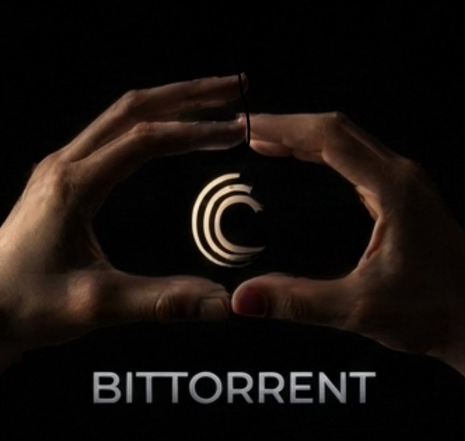 Two hands frame the BitTorrent logo (three curved arcs forming a "B") against a dark background, with the word "BITTORRENT" displayed in white text below—visually evoking the protective, encompassing role the network plays in transforming idle global storage capacity into decentralized infrastructure.