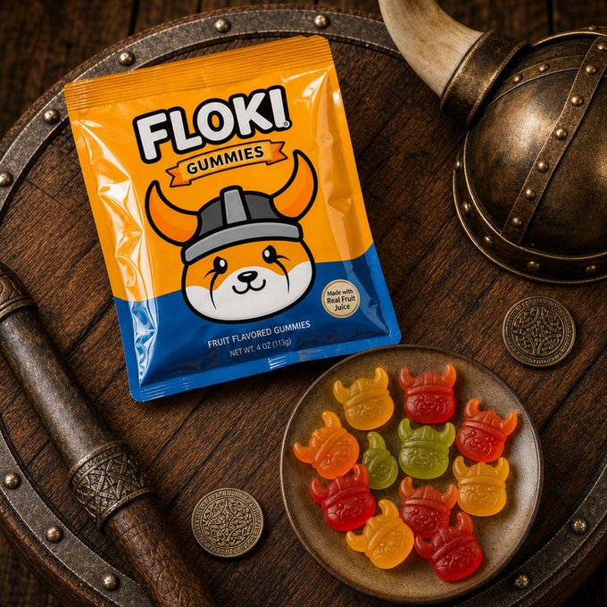 A vibrant orange and blue package of "FLOKI GUMMIES" labeled as "Fruit Flavored Gummies" (4 oz / 113g, made with real fruit juice) sits on a wooden shield alongside a plate of horned viking-shaped gummies in assorted fruit colors, perfectly matching the playful caption by inviting viewers to try the Viking-themed treats.