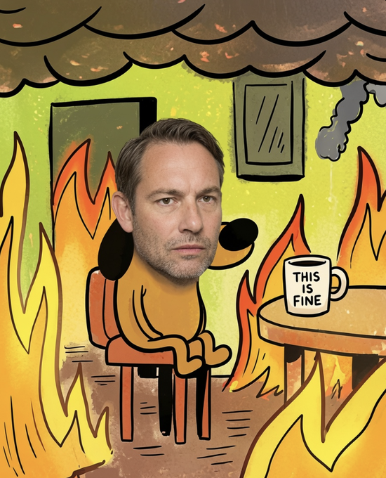 A meme combining the 'This Is Fine' cartoon dog with a real man's face, sitting calmly in a chair drinking coffee while flames engulf the room around him.