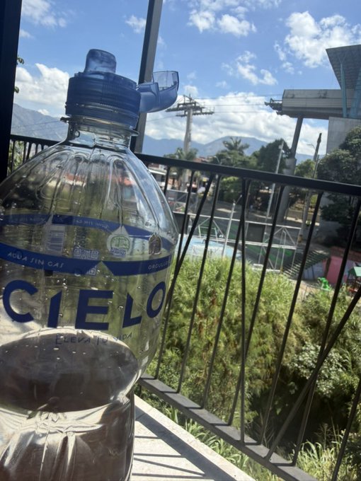 An empty "CIEL9" (Cielo) water bottle sits on a balcony with a scenic mountain view, humorously suggesting the poster has already drained their motivation after a glass of "Cielo" — a Spanish pun playing on "cielo" (sky) and the "CIELO" crypto token.