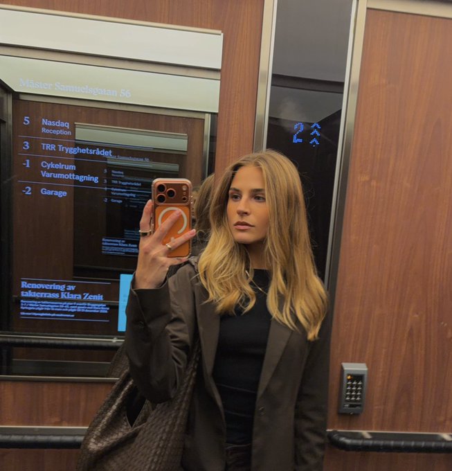 A woman takes a photo in an elevator mirror at Mäster Samuelsgatan 56, with the Nasdaq directory showing directions to Reception, TRR Trygghetsrådet, Cykelrum, and Garage alongside "Recovering av kakelkrans Klara Zenit" text. The image captures the setting of the Nasdaq Stockholm visit mentioned in the post about engaging Nordic investors on bitcoin exposure.