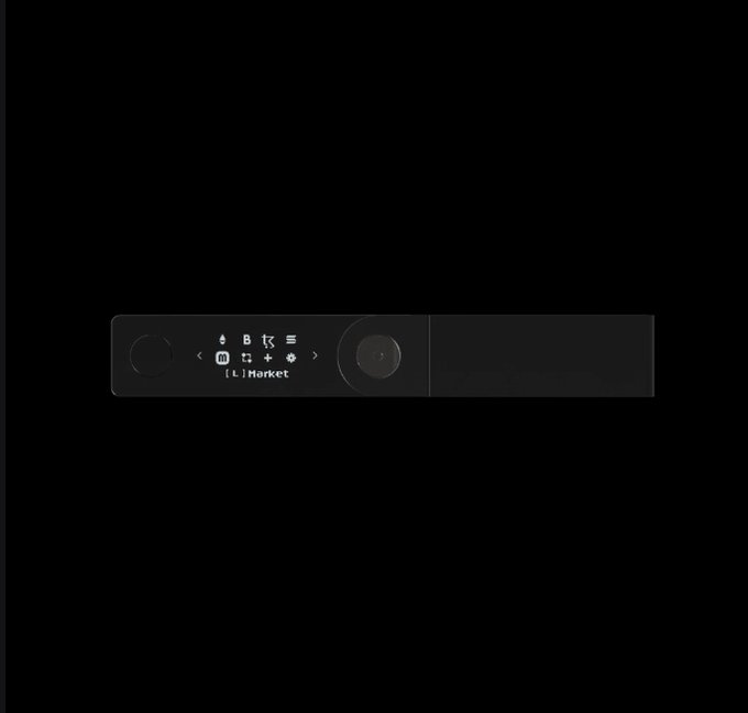 A sleek black Ledger hardware wallet device is displayed against a black background, featuring a small screen showing the "Market" menu with navigation icons and buttons. This ties directly to the post, as the device shown is the Ledger hardware wallet used to store the referenced Redemption Token NFTs.