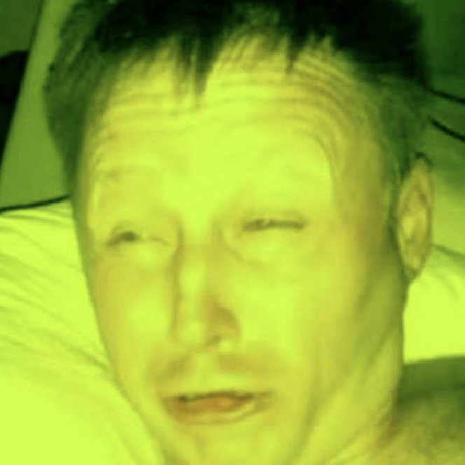 A close-up selfie of a man with short dark hair, heavily filtered with a bright yellow-green tint.