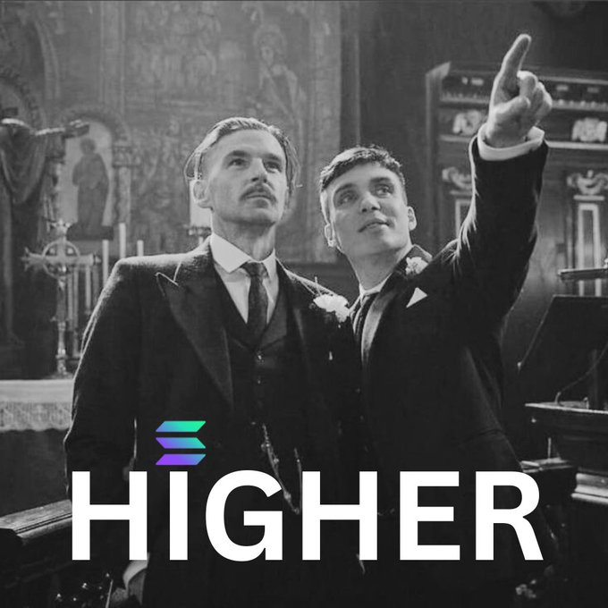 The image features two men dressed in suits, standing next to each other with their arms raised high above their heads. They are both pointing upwards towards something that appears to be a banner or sign. The text "HIGHER" is written below them, which suggests they might be at an event or gathering where the banner has some significance.