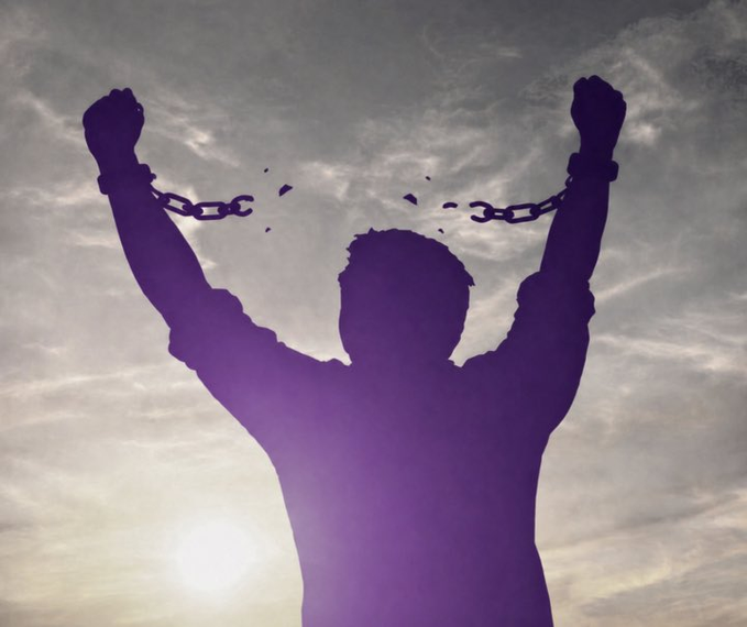 A silhouette of a person with raised arms breaking free from chains, tinted in purple against a bright, cloudy sky with the sun shining through.