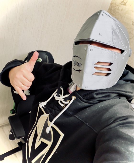 A selfie of a person wearing a gray knight-style helmet with the word 'Bounce' written on it, a black hoodie with a white drawstring, and sitting in a gaming chair while making a hand gesture.