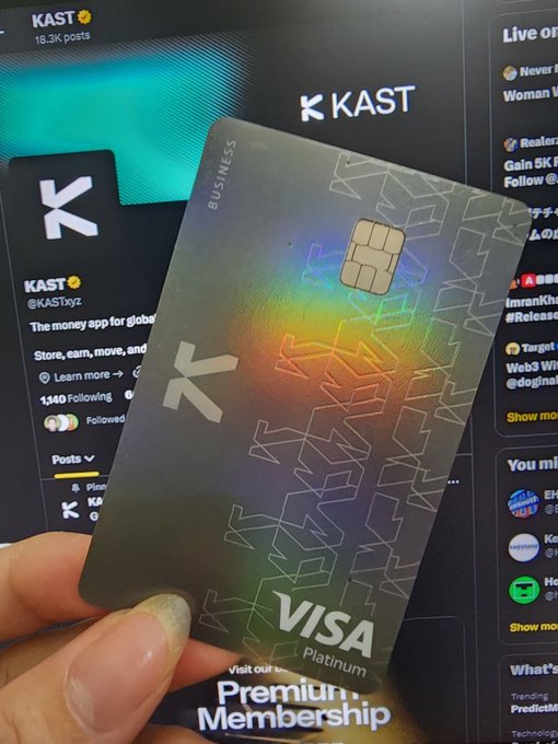 The image shows a person holding up a Visa credit card, which has a rainbow-colored design on its front. The post suggests that the first purchase one would be using this KAST Card for a premium membership.